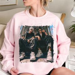 a woman sitting on a couch wearing a pink sweatshirt